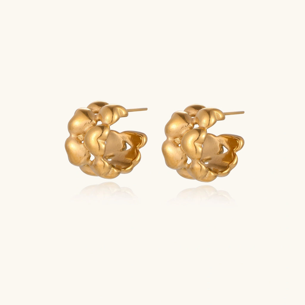 Close-up of gold-plated twisted rope huggie hoop earrings with brushed finish on white background.